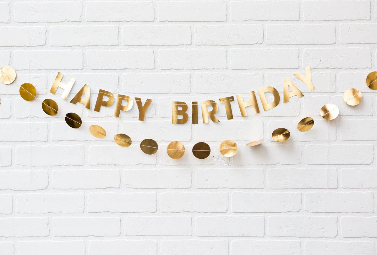 Gold 'Happy Birthday' banner on a white brick wall background
