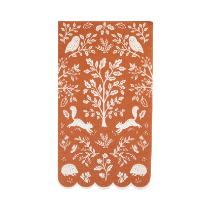 Rust-colored paper dinner napkin with white forest woodland pattern.
