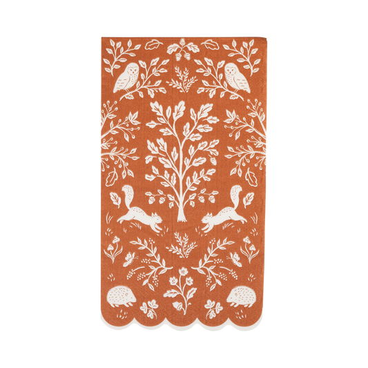 Rust-colored paper dinner napkin with white forest woodland pattern.