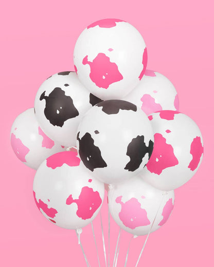 A bouquet of assorted balloons with cow print design on a pink background.