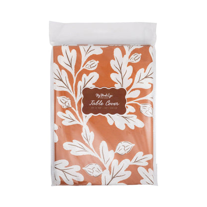 A packaged table cover featuring a terracotta orange background with a white botanical leaf pattern and a central brown label.