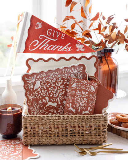 Decorative basket with 'Give Thanks' sign, candles, and autumn-themed items on a table.