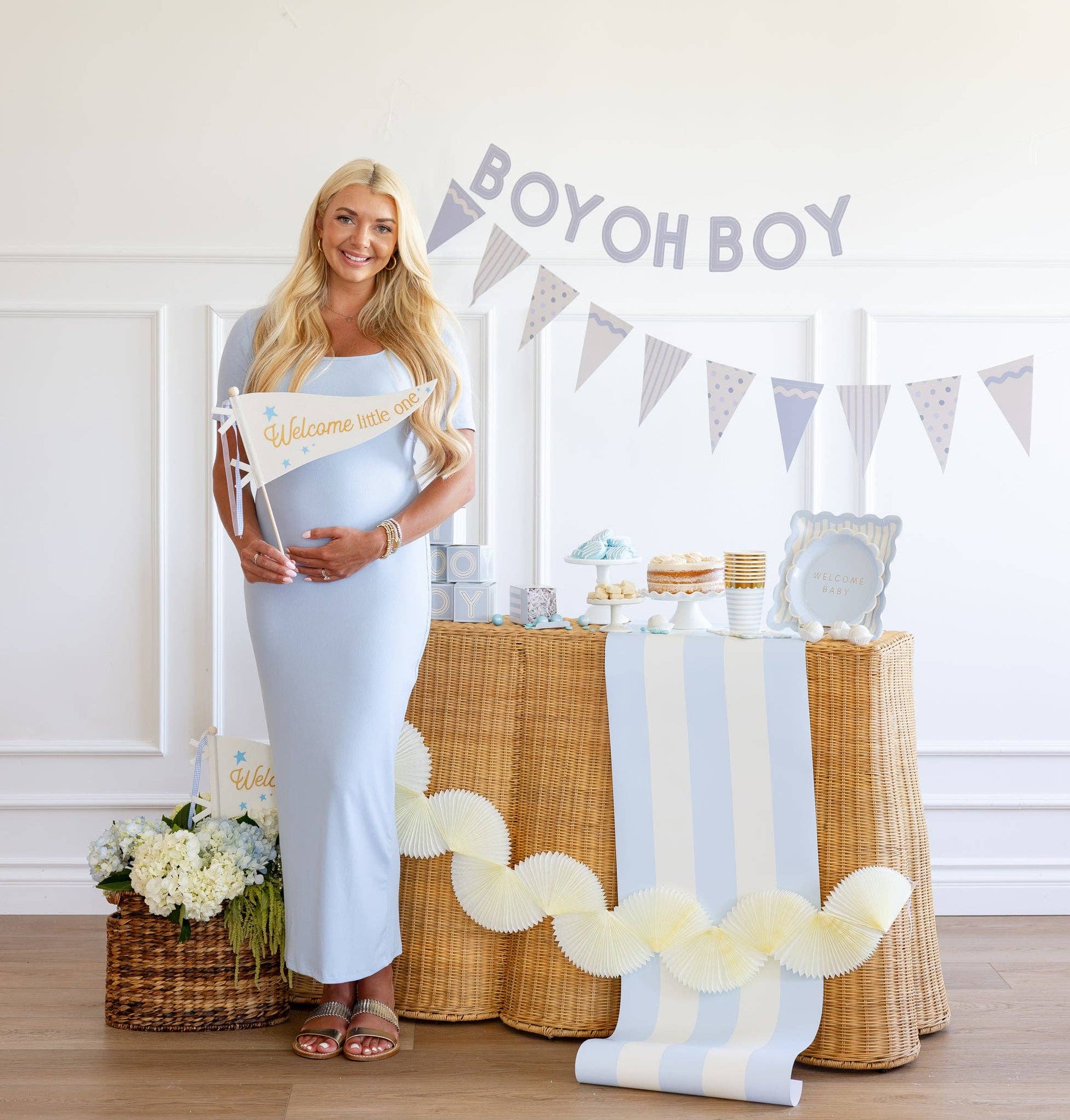 Pregnant woman standing in front of a decorated table with 'Boy oh Boy' banner