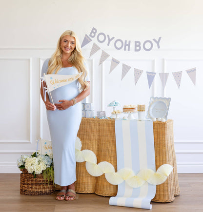 Pregnant woman standing in front of a decorated table with 'Boy oh Boy' banner
