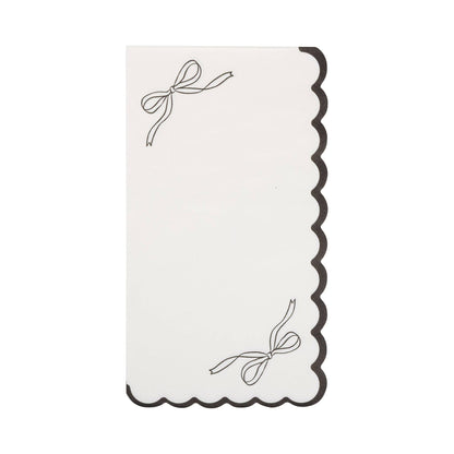 Decorative white napkin with black scalloped edge and bow design on a white background