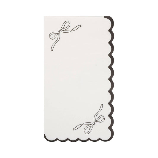 Decorative white napkin with black scalloped edge and bow design on a white background