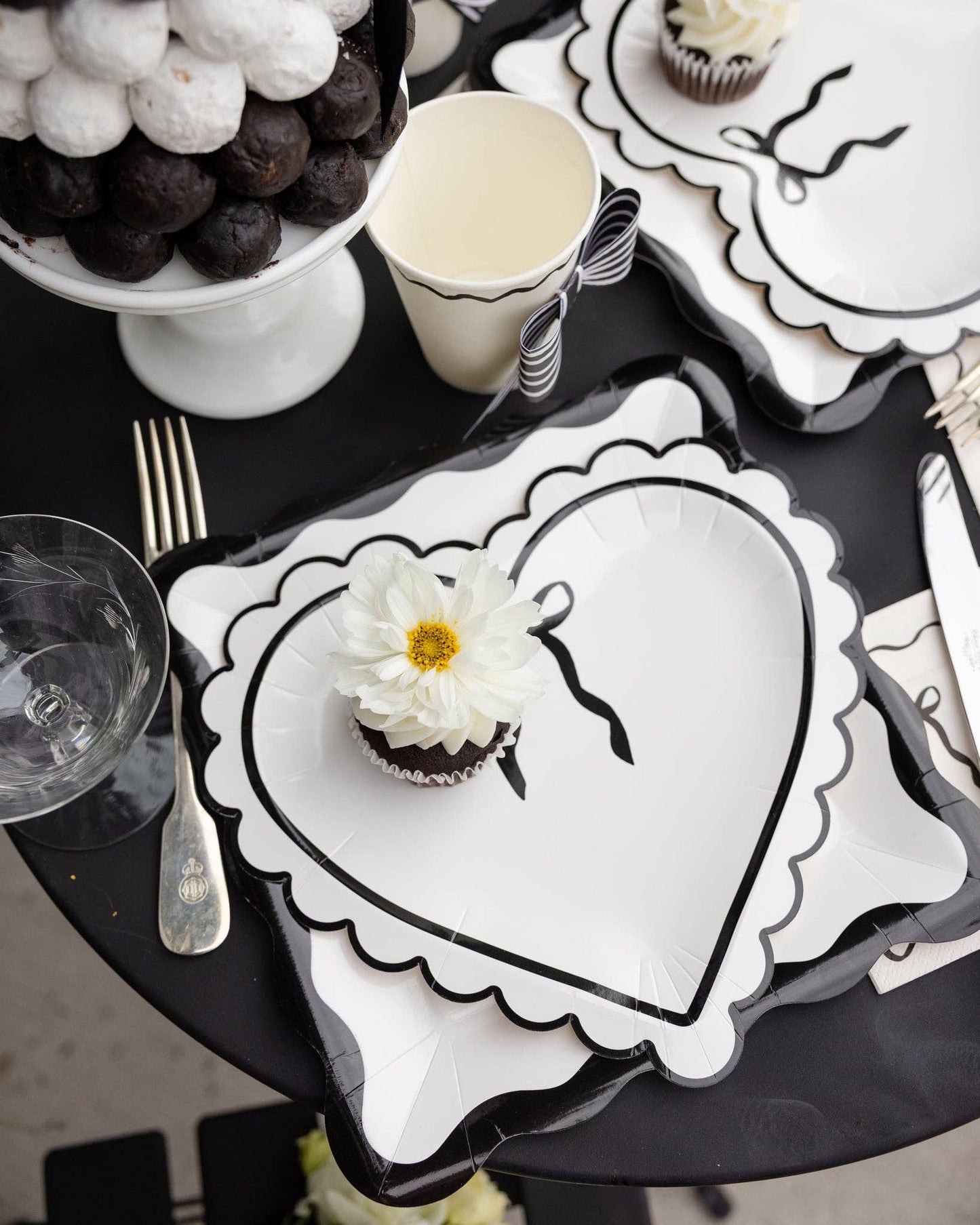 Black and white table setting with a heart-shaped plate and cupcake.