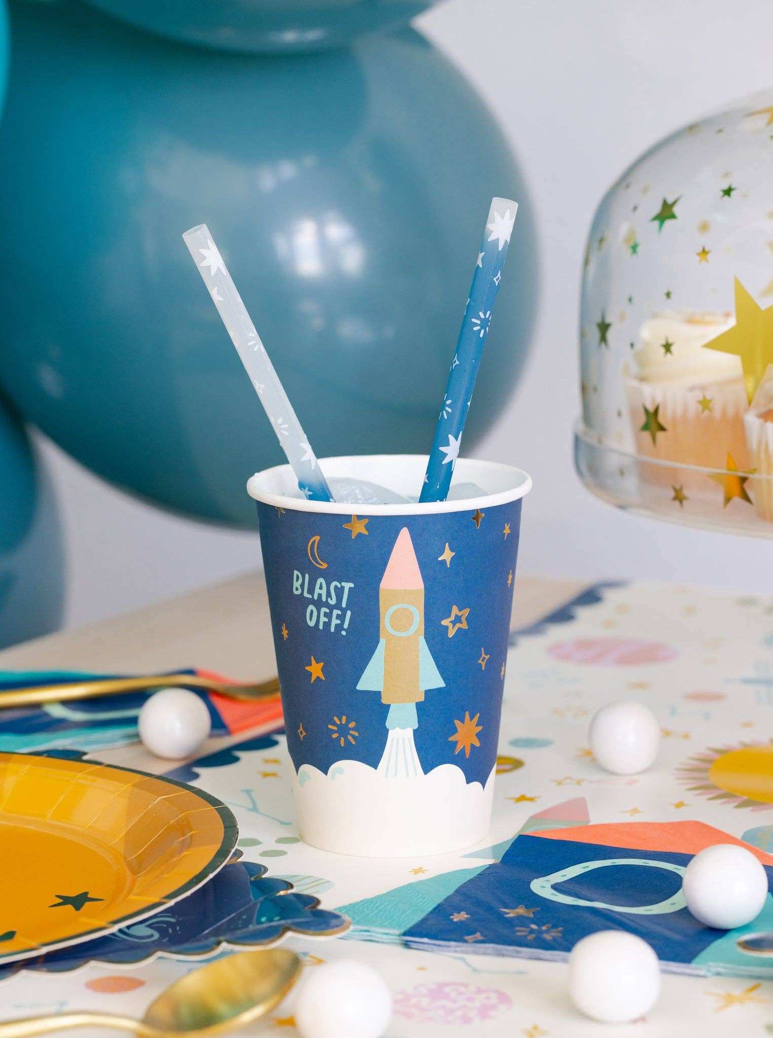 Party cup with rocket design and straw on a table with space-themed decorations