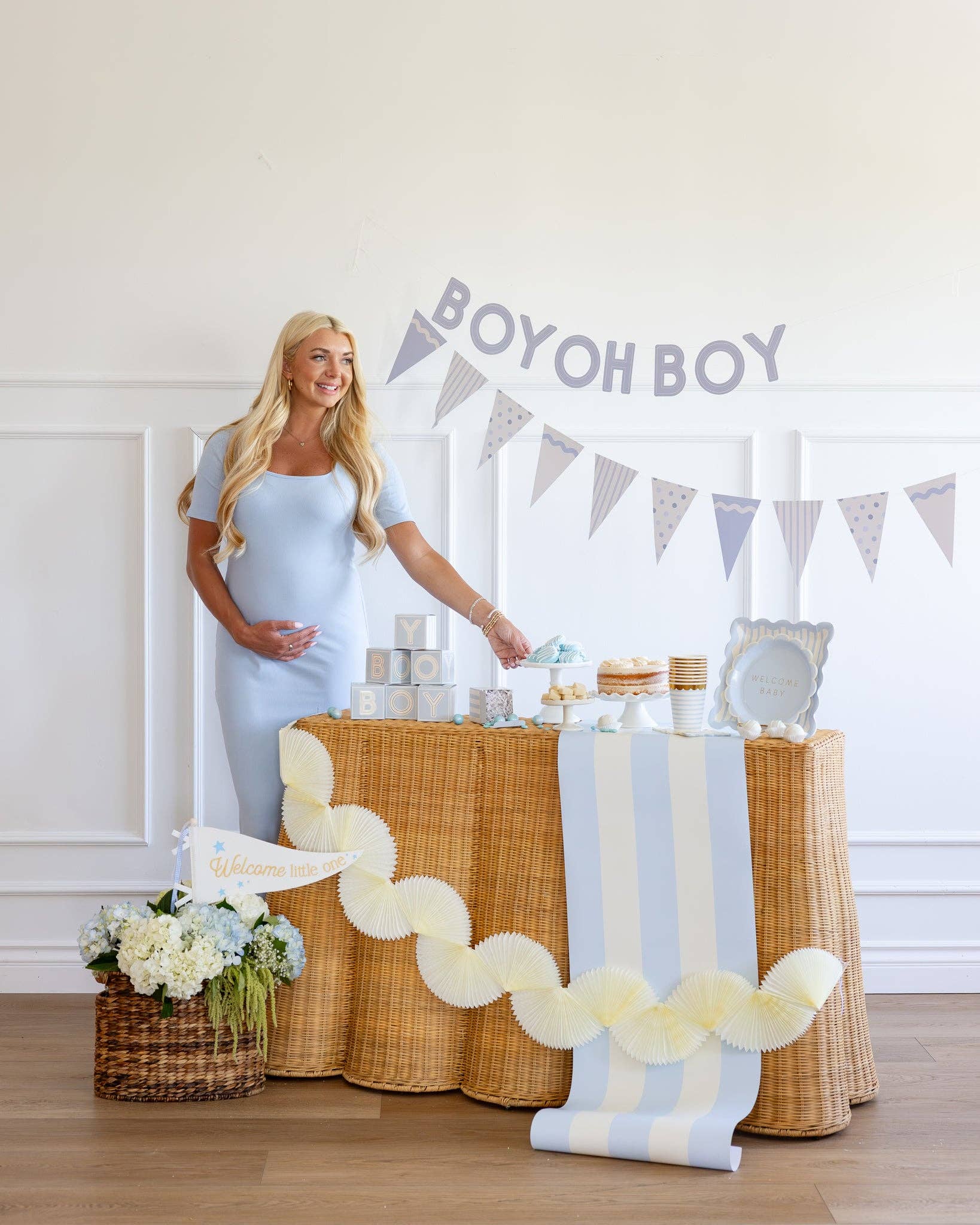 Woman standing next to a baby shower dessert table with 'BOY OH BOY' banner.