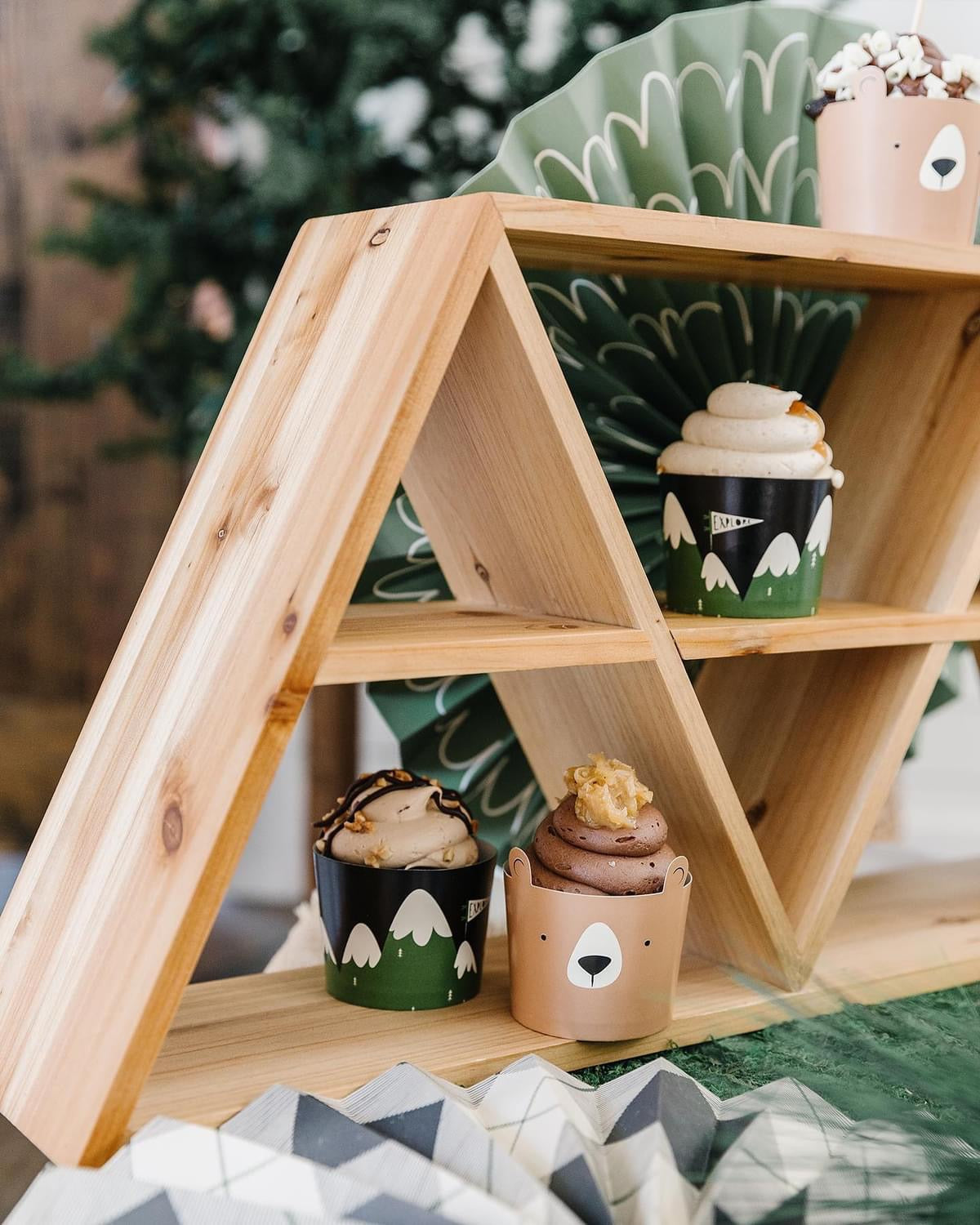 Wooden shelf with decorative items including small cups with animal faces on a soft surface.