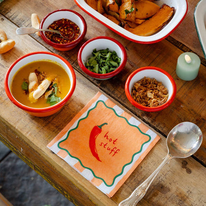 Dishes of food on a wooden table with a 'hot stuff' napkin.