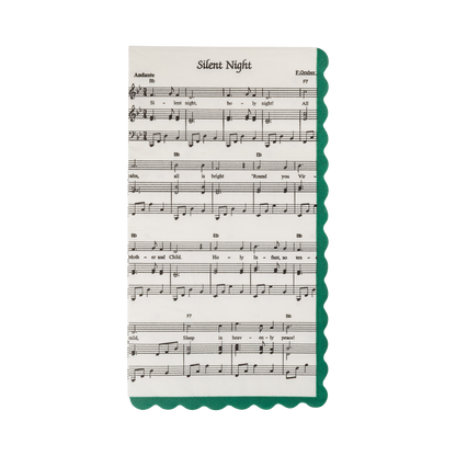 A paper napkin resembling sheet music print for the song 'Silent Night' in C major, featuring musical notation and lyrics, with a decorative green scalloped border on the right side, shown on a plain white background.
