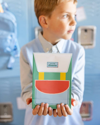 Child holding a colorful party favor in a backpack design against a blue lockers.