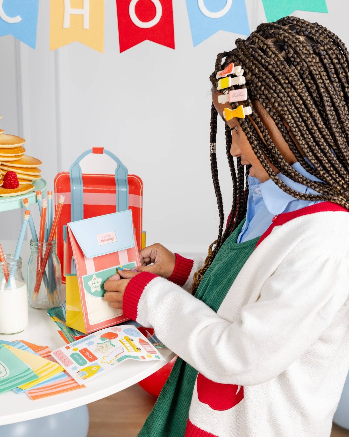 Child decorating backpack treat bag at a table with a back to school breakfast.