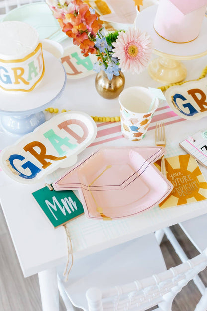 Graduation-themed party supplies including plates, cups, and napkins on a table.