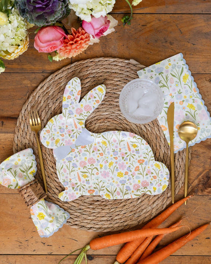 Easter-themed place setting with bunny-shaped paper plates, matching napkins, and carrots on a wooden table.