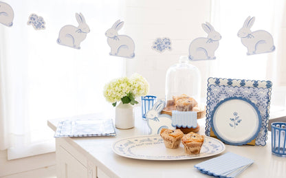 Easter-themed table setting with bunny decorations, muffins, and a floral arrangement.