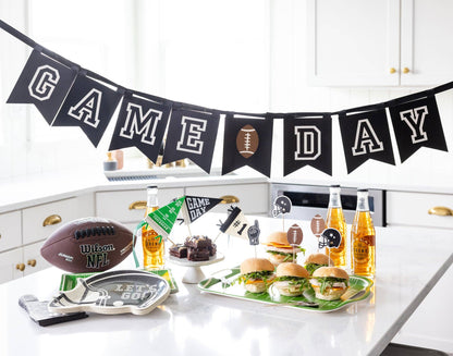 Kitchen counter with 'Game Day' banner, food, and drinks for a sports-themed gathering.