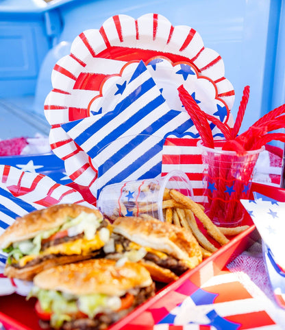 American flag-themed party supplies with burgers and fries on a table.