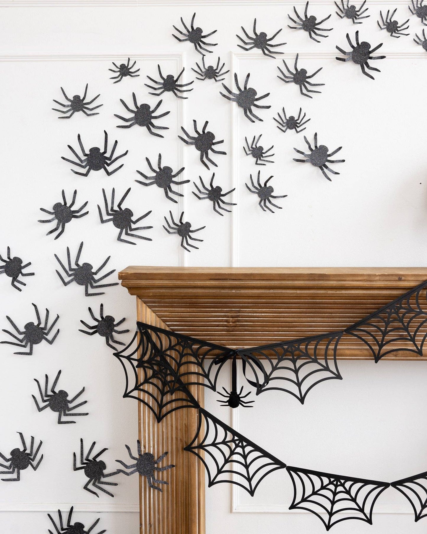 Halloween decorations with black spiders and webs on a white wall.