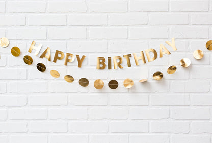 Gold 'Happy Birthday' banner on a white brick wall background