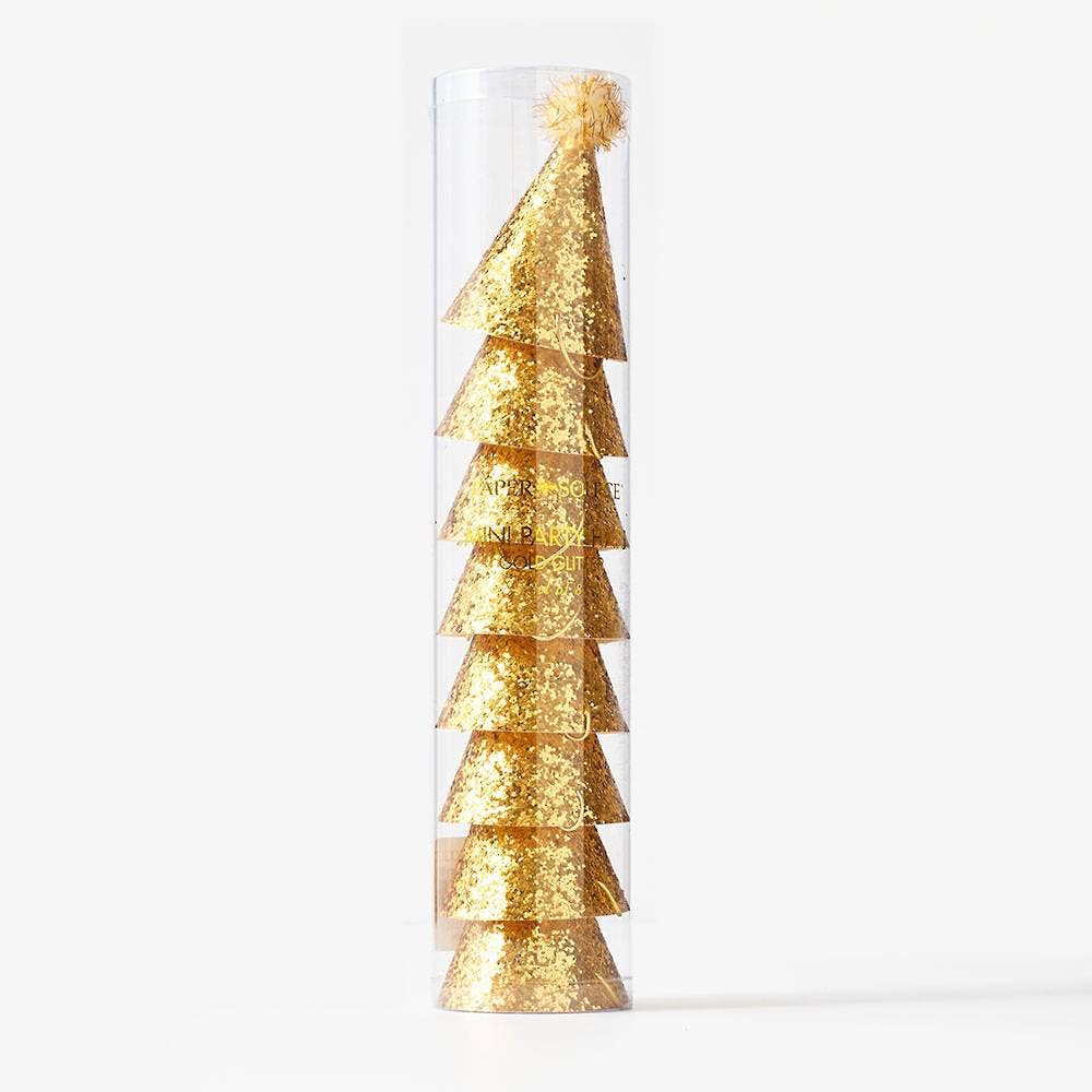 Gold glitter party hats with pom-poms stacked inside packaging on a white background