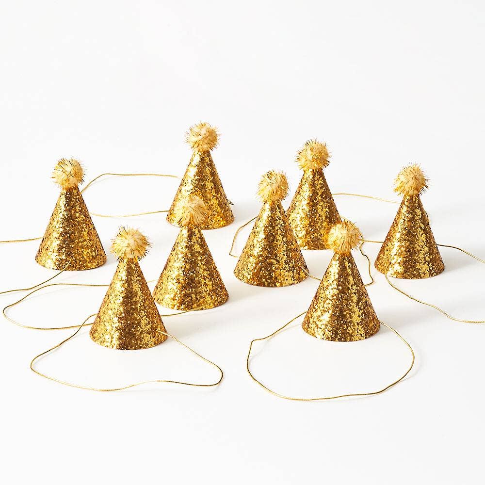 Gold glitter party hats with pom-poms on a white background