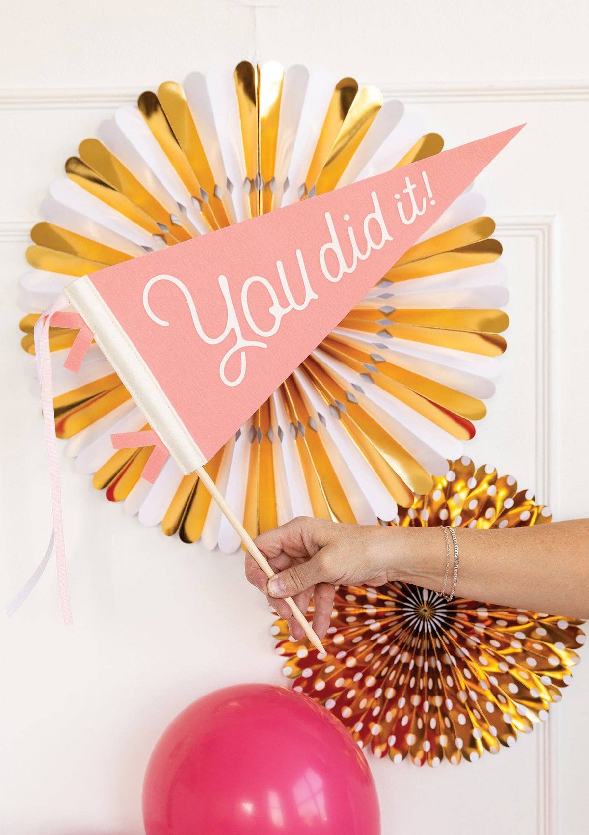 Gold decorative fans with 'You did it!' banner and pink balloon on a white background