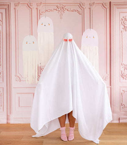 Person wearing a ghost costume with pink shoes in a room with decorative pink walls.