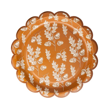 Decorative plate with white leaf and acorn design on an orange & brown background.