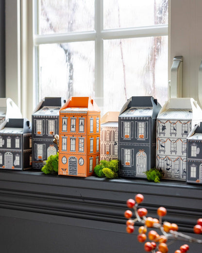 Halloween Village House Treat Boxes on a windowsill with a rainy landscape outside.