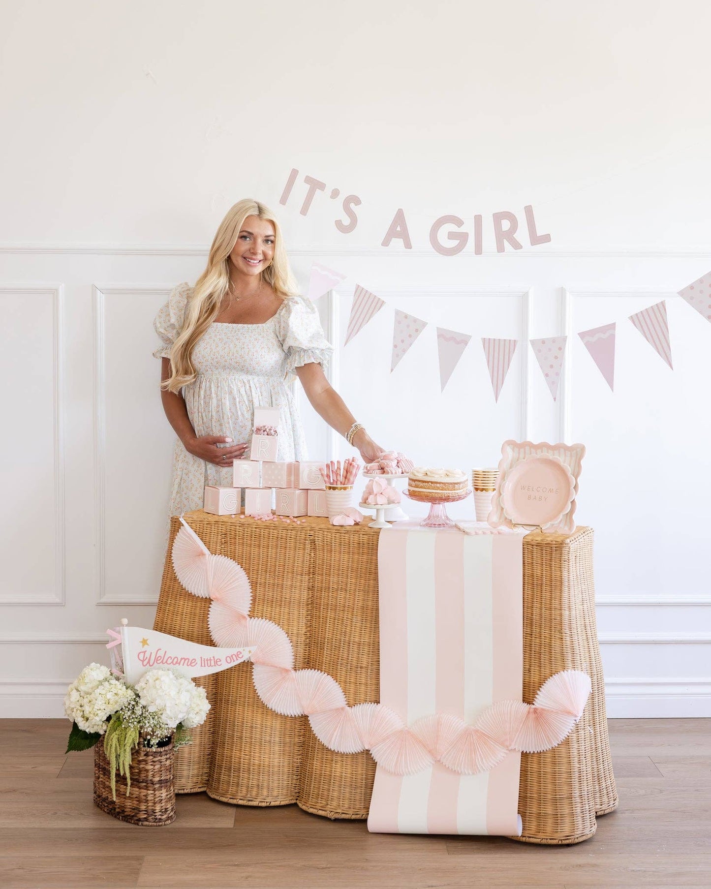 Woman standing behind a decorated table with 'It's a Girl' banner and baby shower items.