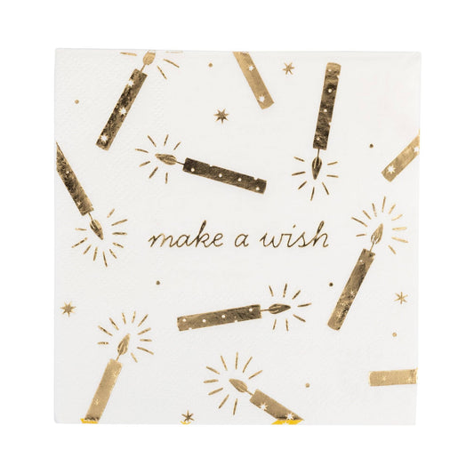 A square white paper napkin featuring a gold foil print of birthday candles, sparkles, and the words 'make a wish' in gold script.