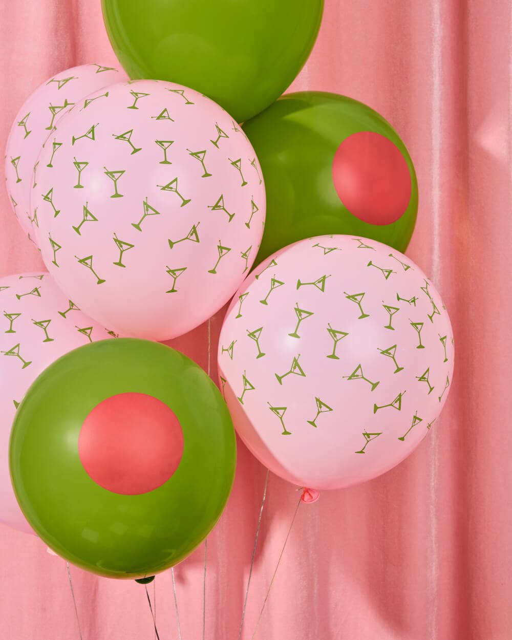 Pink and green balloons with cocktail patterns along with olive balloons against a pink background