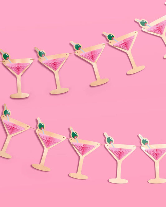 Martini glass garland with pink and green decorations on a pink background