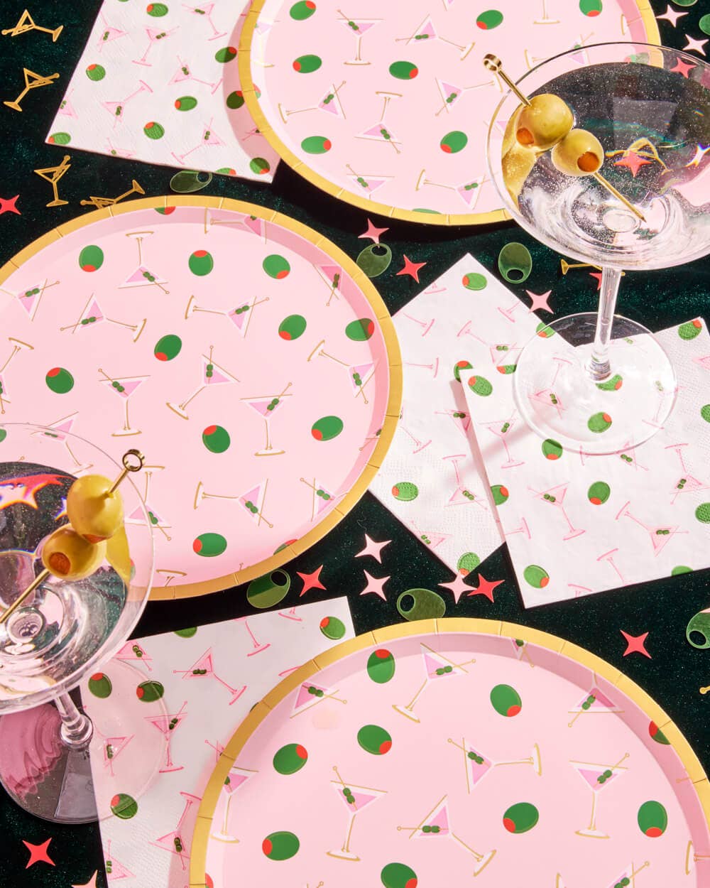 Party supplies with pink plates, napkins, and glasses featuring cocktail-themed designs.