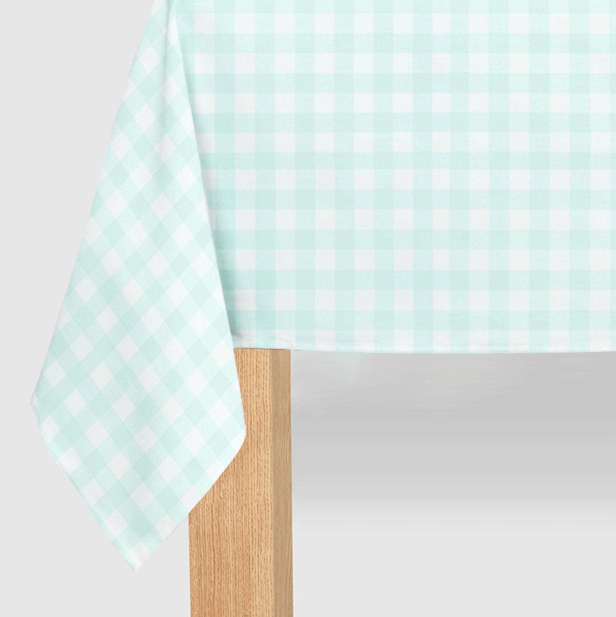 A paper tablecloth with a mint green and white gingham pattern draped over a table.