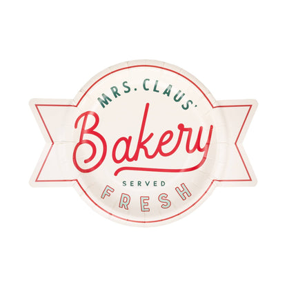 Paper plate in the shape of a logo of Mrs. Claus' Bakery with a decorative border on a white background.