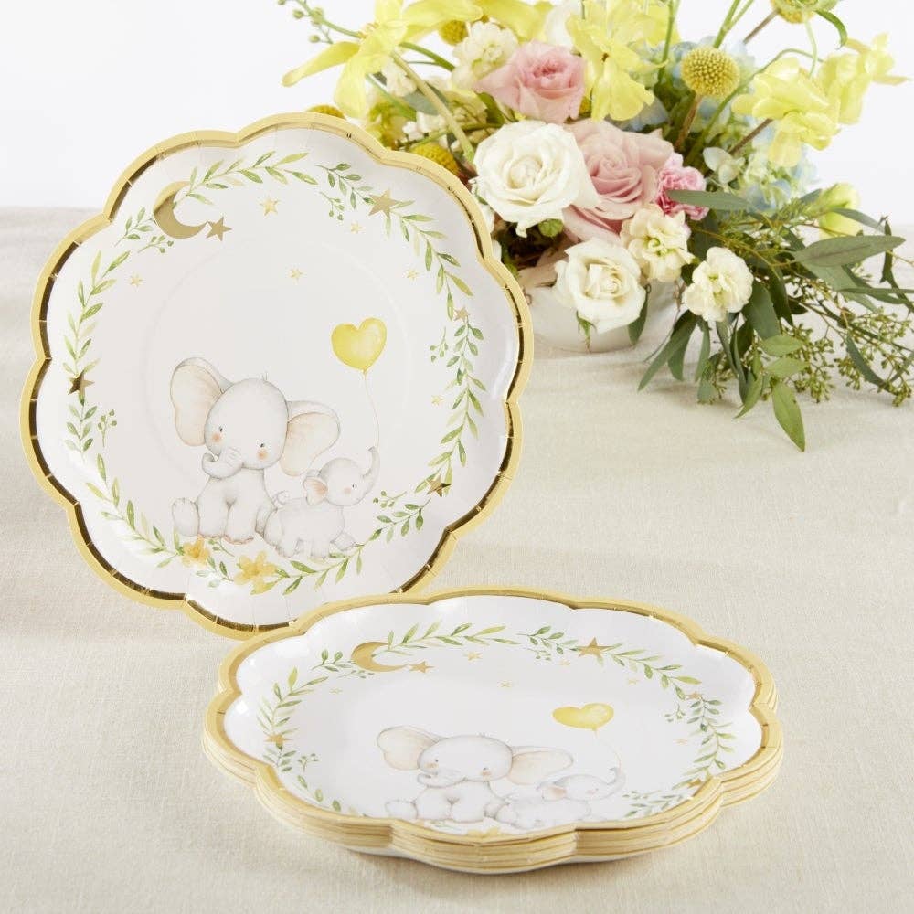 Large white paper plates with elephant designs and gold foil trim on a light surface with flowers in the background.
