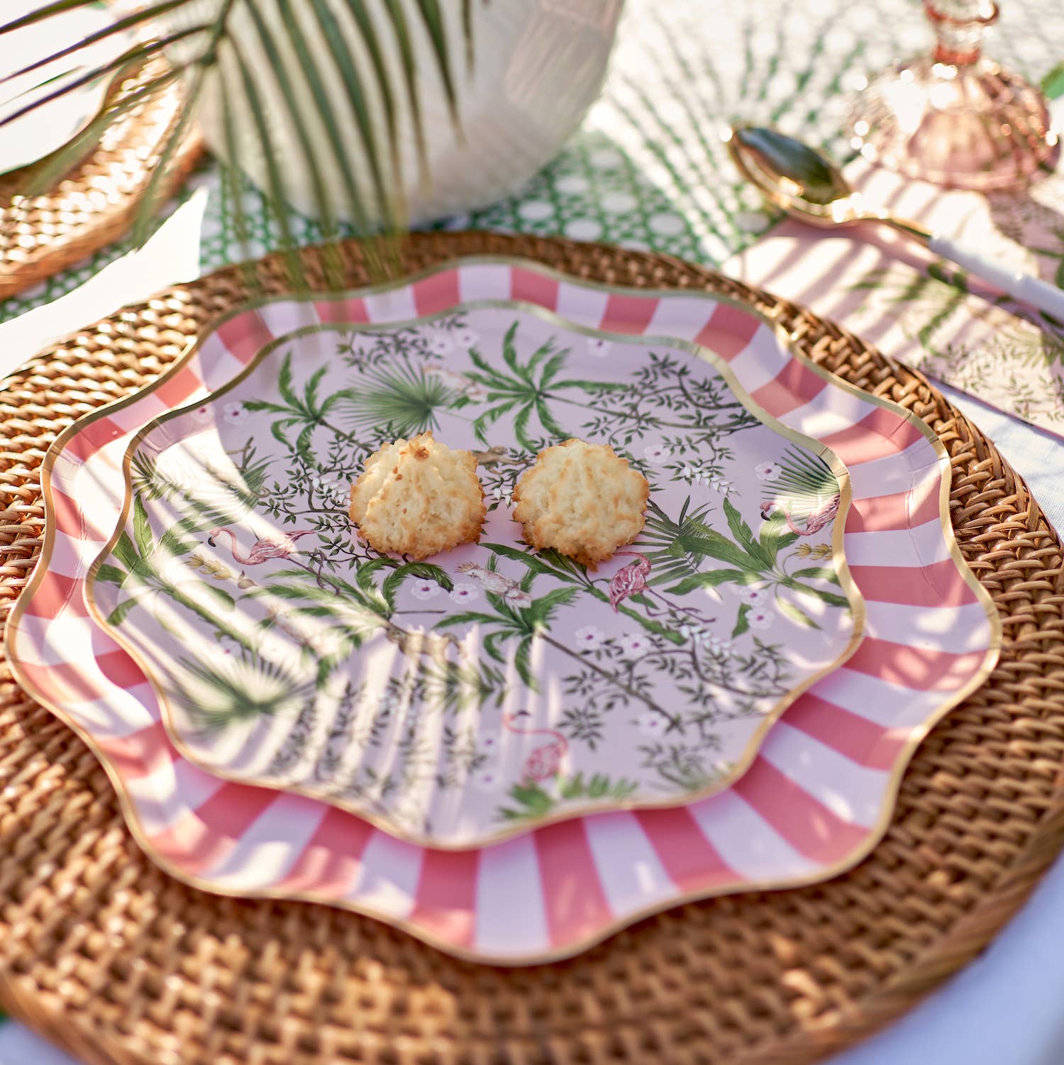 Decorative plates with flamingo design and pink stripes, containing cookies on a wicker surface.