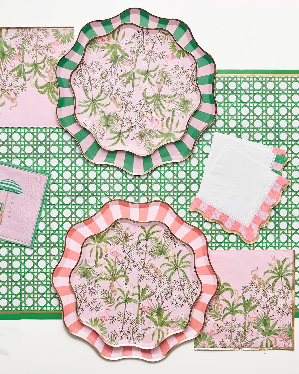 Set of decorative plates and napkins with summery floral patterns on a green rattan patterned paper table runner.