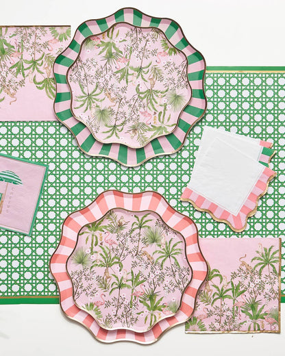 Set of decorative plates and napkins with summery floral patterns on a green rattan patterned paper table runner.