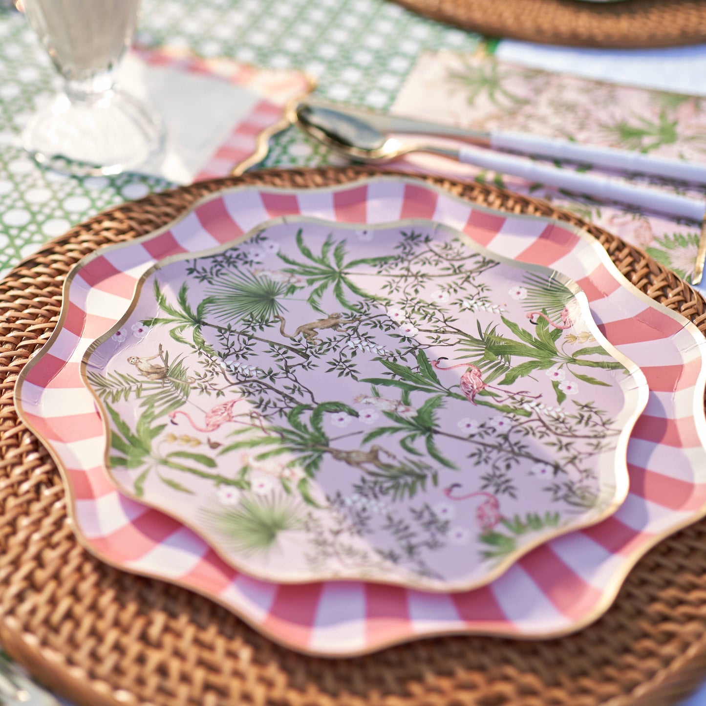 Decorative plate with tropical pattern on top of a larger plate with a cabana striped border, placed on a woven placemat.