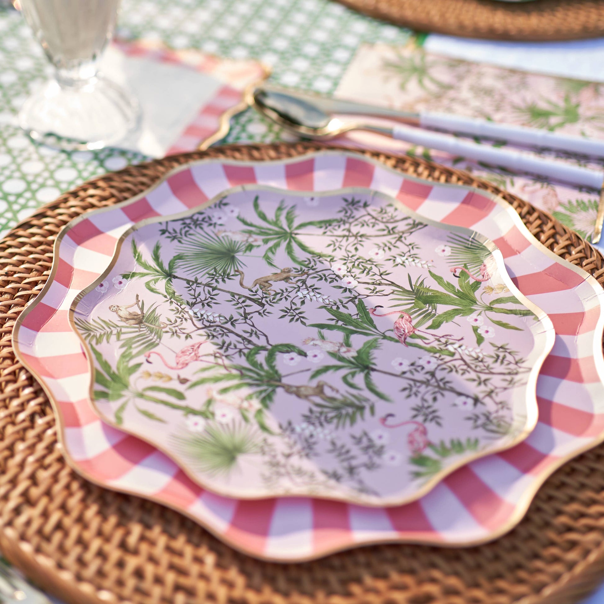 Decorative plate with tropical pattern on top of a larger plate with a cabana striped border, placed on a woven placemat.