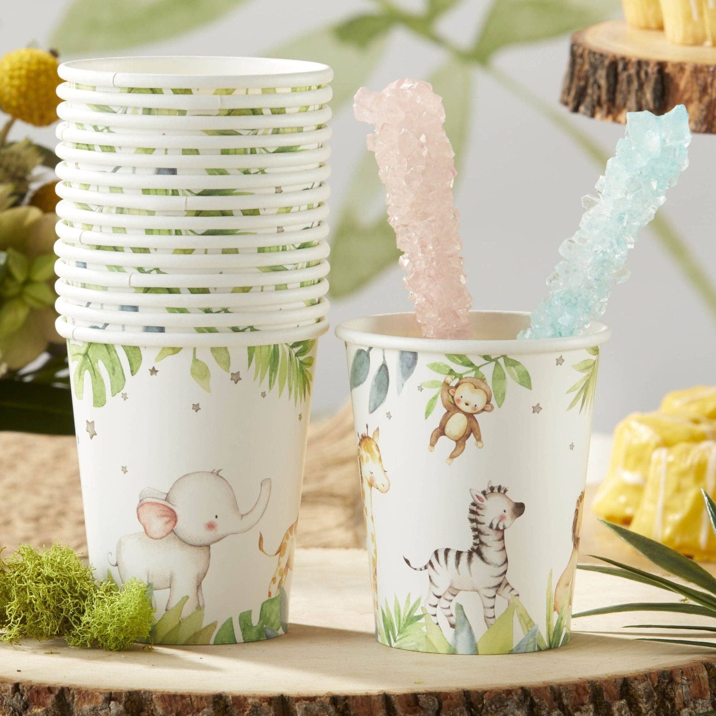 Jungle safari-themed paper cups with animal illustrations on a tree slice.