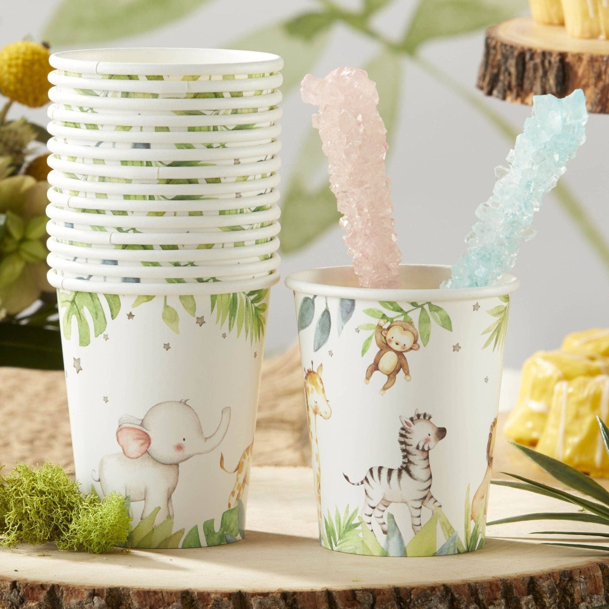 Jungle safari-themed paper cups with animal illustrations on a tree slice.