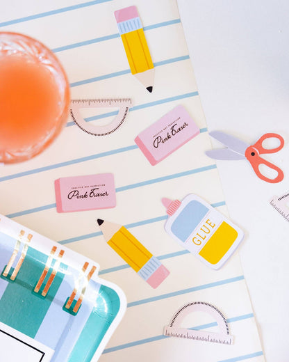 Colorful confetti including a pencil, glue stick, and scissors on a striped background.