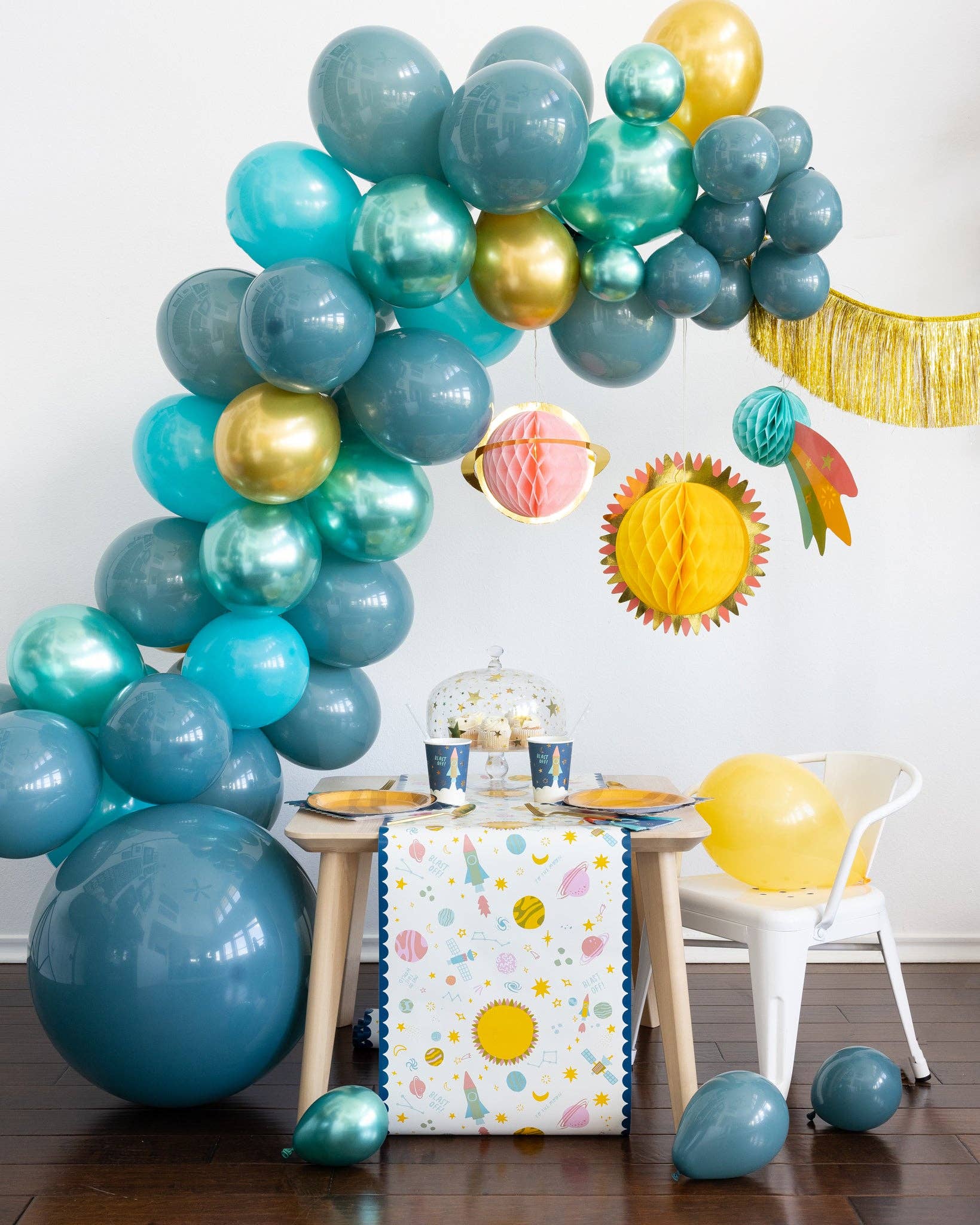 Colorful balloon arch with a table and space decorations in a room.