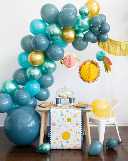 Colorful balloon arch with a table and space decorations in a room.