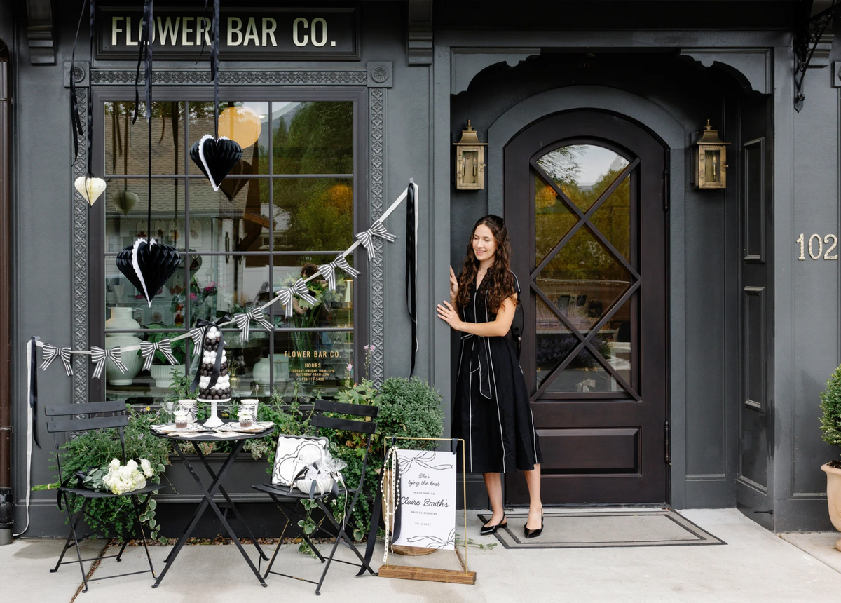 Woman standing outside a flower shop named 'Flower Bar Co.'